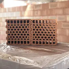 Blocchi forati in laterizio, ideali per l'isolamento acustico, impilati su un bancale.