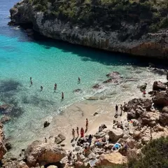 Malownicza zatoczka z turkusową wodą, skaliste wybrzeże i plażowicze. Idealne miejsce na egzotyczne wakacje.