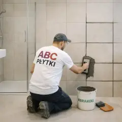 Fachowiec nakłada fugę na płytki w łazience. Czas, ile schnie fuga, zależy od wielu czynników.
