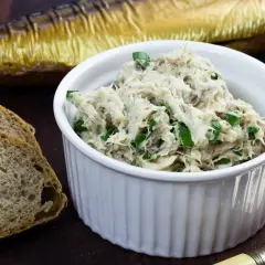 Pyszna pasta z makreli i twarogu, posypana szczypiorkiem, obok kromek chleba i wędzonej makreli.