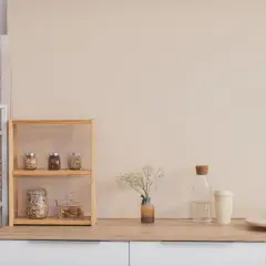 Regale mit Vorräten, Ölflaschen und Pflanzen zeigen **minimalismus im alltag**. Eine Vase mit Trockenblumen und eine Wasserflasche ergänzen die Szene.