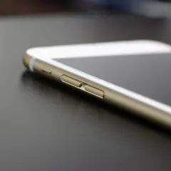Złoty telefon leży na ciemnym blacie. Dowiedz się, jak sprawdzić lokalizację telefonu, by mieć pewność, że jest bezpieczny.