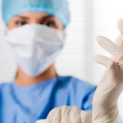 Ärztin zieht Handschuhe an. Der PSA-Wert ist wichtig für die Sicherheit.