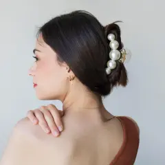 Elegante claw clip frisuren mit Perlen verzieren den Dutt einer Frau.