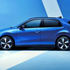 El nuevo Volkswagen ID.2, un coche eléctrico azul brillante, se presenta en un estudio con un fondo azul y líneas blancas.