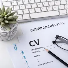 Na biurku leżą dokumenty CV, klawiatura i okulary. To miejsce pracy, gdzie liczy się wykształcenie i doświadczenie.