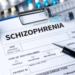 Lekarz wypełnia formularz "Schizofrenia", obok leżą strzykawki, stetoskop i opakowania leków, w tym risperidon.