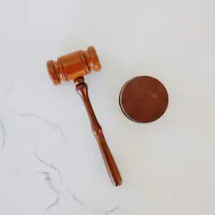 Drewniany młotek sędziowski i okrągły drewniany blok na białym tle.