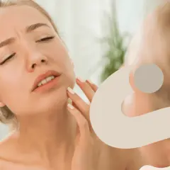 Donna con viso irritato che si tocca la guancia, preoccupata per la sua pelle.