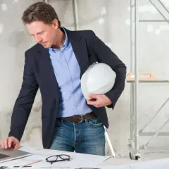 Inspektor sprawdza co sprawdza nadzór budowlany przy odbiorze budynku, analizując plany na laptopie.