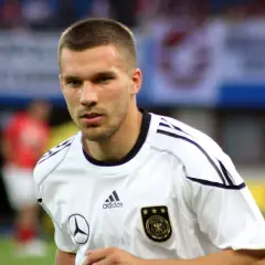 Piłkarz w białej koszulce reprezentacji Niemiec, z orłem i trzema gwiazdkami. To młody Podolski, gotowy do gry.
