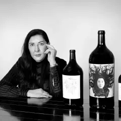 Donna con le migliori annate Ornellaia. Le bottiglie presentano etichette artistiche, una con un ritratto.