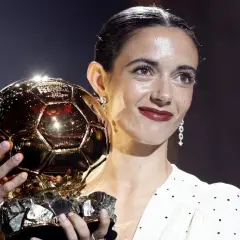 Piłkarka z dumą trzyma złotą piłkę kobiet, symbol najwyższego uznania w świecie futbolu.