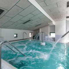 Piscina de hidromasaje con chorros de agua y cascada central en un balneario.