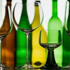 Leere Weingläser stehen vor bunten Flaschen. Die richtige rotwein temperatur ist entscheidend für den Genuss.