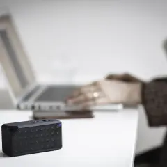 Mały głośnik z niebieską diodą obok laptopa. Dowiedz się, jak sprawdzić, czy komputer ma Bluetooth.