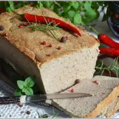 Pyszny pasztet mieszany drobiowo-wieprzowy, udekorowany papryczką chili i ziołami, gotowy do podania na kromce chleba.