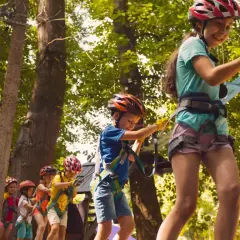 Dzieci w kaskach pokonują park linowy, świetna zabawa i **bieszczady atrakcje dla dzieci**.