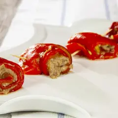 Peperoncini ripieni alla piemontese, rotolini rossi con ripieno saporito, serviti su un piatto bianco.