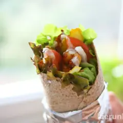 Pyszna tortilla z kurczakiem, świeżymi warzywami i sosem, gotowa do zjedzenia.