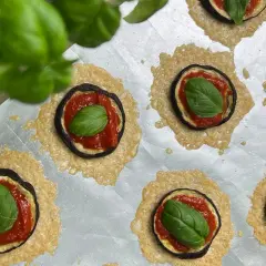Kleine Aubergine-Pizza-Häppchen mit Tomatensoße, Käse und frischem Basilikum auf einem Backblech.