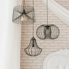 Nowoczesne **lampa pająk aranżacje** w loftowym stylu. Trzy wiszące lampy z drucianymi kloszami na tle ceglanej ściany i białej zasłony.