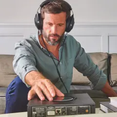 Mężczyzna w słuchawkach reguluje urządzenie audio, sprawdzając jego impedancję słuchawek.