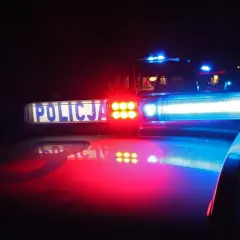 Policyjne światła błyskają w ciemności, sygnalizując sytuację wymagającą obrony koniecznej.