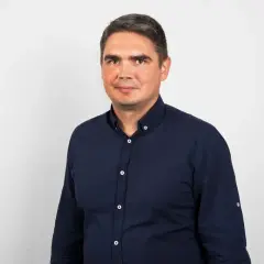 Portret mężczyzny w granatowej koszuli na jasnym tle.