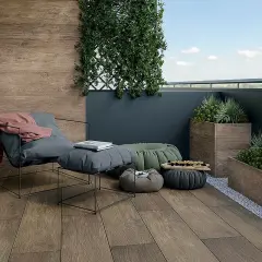 Drewnopodobne płytki na balkon tworzą przytulną atmosferę. Wygodny fotel, pufy i rośliny zapraszają do relaksu.