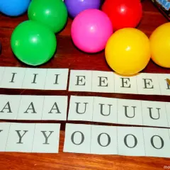 Kolorowe piłeczki i paski z literami: I, E, A, U, Y, O. Czy to nauka, ile jest samogłosek w języku polskim?