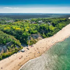 Widok z lotu ptaka na piaszczystą plażę w Jastrzębiej Górze z klifem i lasem.
