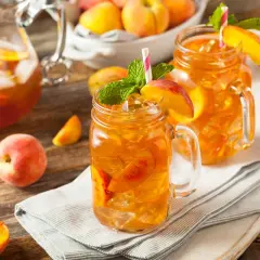 Orzeźwiająca, domowa ice tea z brzoskwiniami i miętą, podana w słoikach z uchwytem. Idealna na upalne dni.