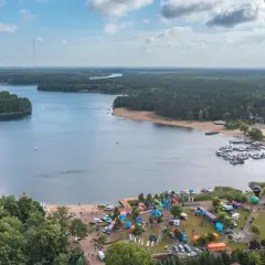 Widok na jezioro Otmuchowskie z lotu ptaka. Widać plażę, przystań jachtową, las i miasteczko z atrakcjami.