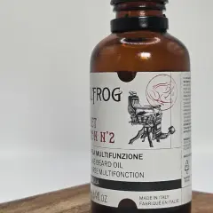 Olej do brody Bullfrog z wizerunkiem żaby i fotela fryzjerskiego.