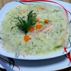 Aromatyczna zupa koperkowa z ryżem, kawałkami kurczaka i marchewką, udekorowana gałązką koperku.