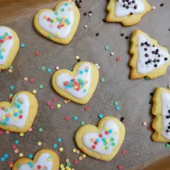 Herzförmige und baumförmige Kekse mit weißer Glasur und bunten Streuseln, bereit zum Verzehr nach dem Kekse backen.