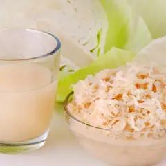 Glas mit Sauerkrautsaft, Schüssel mit Sauerkraut und Weißkohl. Ideal für eine Sauerkrautsaft Kur. Anleitung hier.