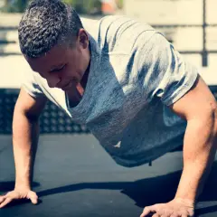 Un homme en plein effort, réalisant des burpees. Son corps est gainé, prêt à repousser le sol.