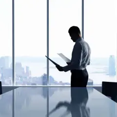 Biznesmen w garniturze analizuje dokumenty w sali konferencyjnej z widokiem na miasto. Czy to jest pct co to?