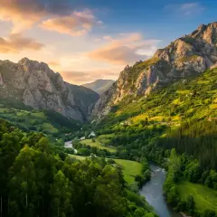Un valle verde con un río serpenteante, montañas escarpadas y un cielo dorado. Parece la senda del oso, un lugar de belleza salvaje.