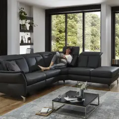 Frau liest auf schwarzem Ledersofa. Dieses Leder ist am robustesten und pflegeleicht, ideal für den Alltag.