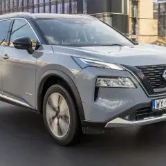 Szary Nissan X-Trail e-POWER w ruchu miejskim. Kierowca testuje jego niskie spalanie.