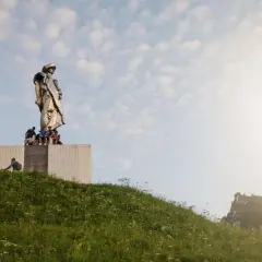 Pomnik Janosika góruje nad wzgórzem, a pod nim siedzą ludzie.