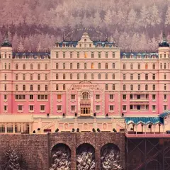 A grand pink hotel with a distinct Wes Anderson aesthetic, nestled in a snowy, purple-hued forest.