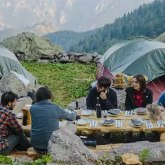 Amici in campeggio, cena all'aperto con vista monti. Un'esperienza ferdy wild indimenticabile tra tende e natura.
