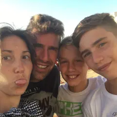 Famiglia in vacanza con ragazzi di 15 anni, sorrisi e sole.