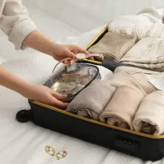 Packa smart för din resa med handbagage. En person organiserar kläder och necessär i en resväska.