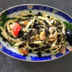 Scialatielli con cozze, pomodorini e una spolverata di pecorino grattugiato, su un letto di salsa verde.