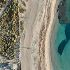 Vista aérea de las playas de Roquetas de Mar con arena fina, vegetación árida y aguas cristalinas.